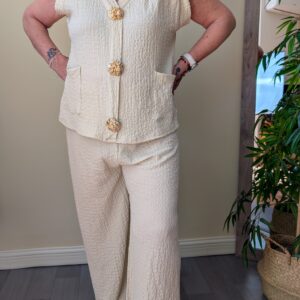 Conjunto de mujer beige compuesto por chaleco texturizado con botones dorados y pantalon palazzo ancho a juego de estilo elegante y sofisticado